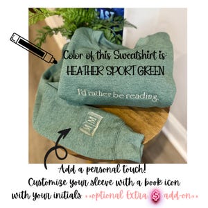 K&ouml;nnte beinhalten: Heather Sport Green Sweatshirt mit dem Text "I'd rather be reading." Der &Auml;rmel hat ein Buchsymbol mit Initialen. Das Bild enth&auml;lt auch den Text "Add a personal touch! Customize your sleeve with a book icon with your initials."
