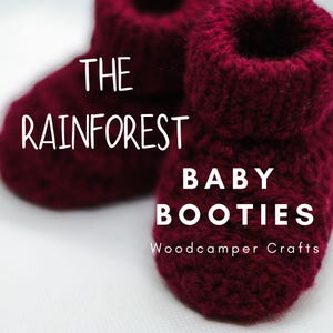 May include: A pair of burgundy knitted baby booties with the text "The Rainforest Baby Booties Woodcamper Crafts".
