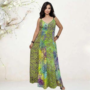 May include: A long, flowing maxi dress with a V-neck and spaghetti straps. The dress features a vibrant green, yellow, and purple floral pattern. The dress is floor-length and appears to be made of a lightweight fabric, suitable for warm weather.