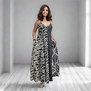 May include: A long maxi dress with a V-neck and spaghetti straps. The dress has a patchwork design with black and white patterns, including geometric shapes and leaf motifs. The dress is floor-length, suitable for warmer weather.