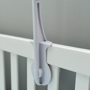 May include: White plastic crib mobile arm with a knob to tighten the arm to the crib rail.