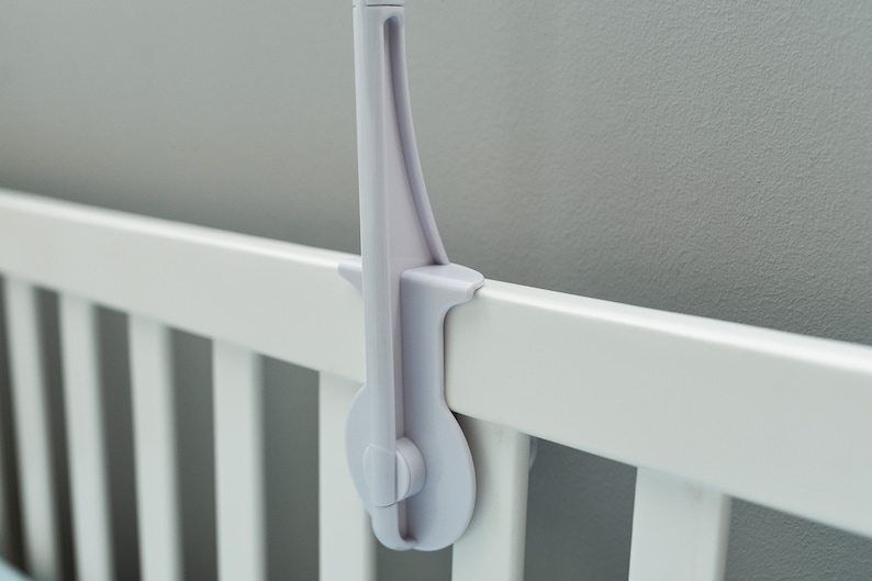 May include: White plastic crib mobile arm with a knob to tighten the arm to the crib rail.