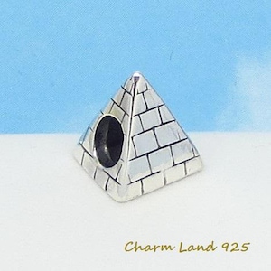 May include: Silver charm in the shape of a pyramid with a brick pattern. The charm has a hole in the center for attaching to a bracelet.