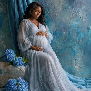 Può includere: Una persona incinta indossa un abito premaman azzurro chiaro con maniche lunghe e scollo a V. L'abito è drappeggiato con eleganza. Sullo sfondo, ortensie blu e un muro blu strutturato.