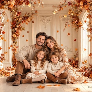 Può includere: Una famiglia di quattro persone seduta davanti a una parete bianca decorata con foglie d'acero autunnali. Il gruppo indossa abiti coordinati nei toni del beige e del marrone, inclusi maglioni e un vestito a fiori, circondato da fogliame arancione e rosso.