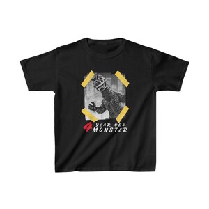 May include: Black t-shirt with a graphic of a monster with the text "4 year old monster" printed on it.