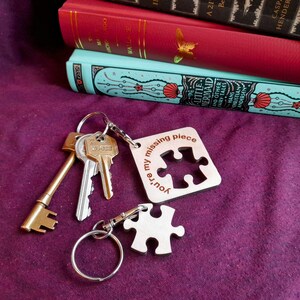 May include: A wooden keychain with a puzzle piece cutout and the text "You're my missing piece". The keychain is attached to a set of keys and a silver keyring.