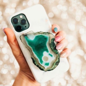 May include: A white phone case with a green and white agate stone glued to the back. The phone case has a triple lens camera.
