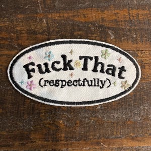 May include: Oval embroidered patch with the words "Fuck That" in black, with "(respectfully)" below. The patch is white with a black border and small floral accents in pink, blue, and yellow.