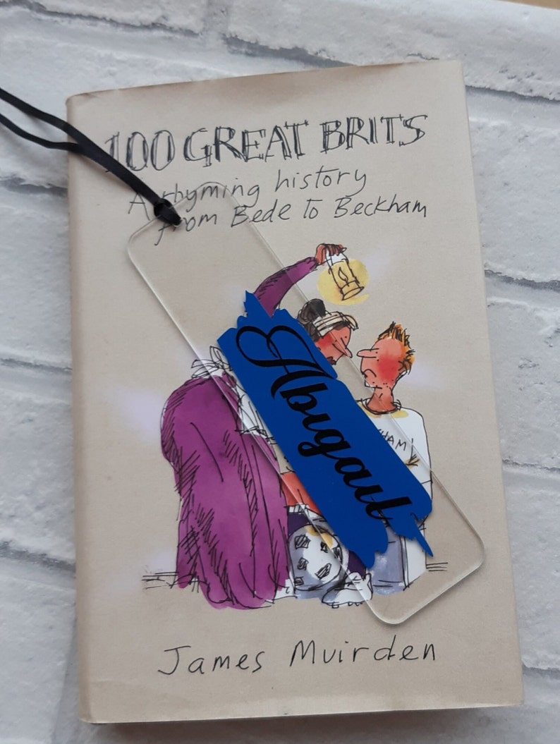 May include: A book titled "100 Great Brits: A rhyming history from Bede to Beckham" by James Muirden. A blue bookmark with the word "Always" written in white is placed on the book.