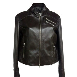 May include: A brown leather jacket with a zipper closure and multiple pockets. The jacket has a stand-up collar and long sleeves.