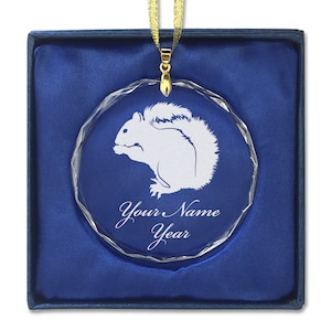 May include: A clear glass ornament with a white silhouette of a squirrel. The ornament is in a blue velvet box with a gold ribbon. The ornament has the text "Your Name Year" engraved on it.