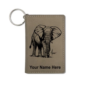 May include: A gray leather keychain with a black and white illustration of an elephant. The keychain has a metal ring and the text "Your Name Here" is printed on the bottom.