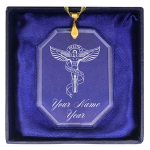 May include: A glass ornament with a gold chain, featuring a white silhouette of a caduceus with the words "Health Chiropractic" and "Your Name Year".