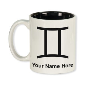 May include: White ceramic mug with a black interior and handle. The mug features a black Gemini zodiac symbol and the text "Your Name Here" printed on the front. The mug is designed for personalization.