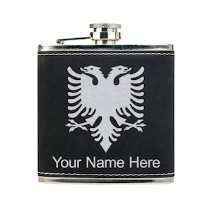 May include: A black leather-wrapped stainless steel flask with a silver cap. The flask features a white double-headed eagle design and the text "Your Name Here".