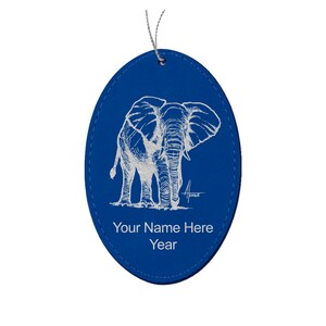 May include: Blue oval leather ornament with a white line drawing of an elephant. The ornament has the text "Your Name Here Year" on the bottom.