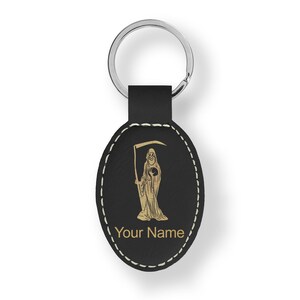 May include: Black leather oval keychain with a gold-colored image of the Grim Reaper holding a scythe and an hourglass. The keychain has a silver key ring and the text "Your Name" is printed below the image.