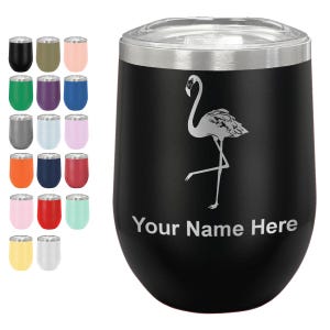 May include: A black stainless steel tumbler with a clear lid, featuring a white engraved flamingo graphic and the text Your Name Here. A grid of eighteen additional tumblers in various solid colors is displayed to the left of the main item.