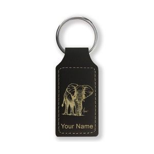 May include: Black leather keychain with a gold engraved image of an elephant. The keychain has a silver key ring and the text "Your Name" is engraved below the image.