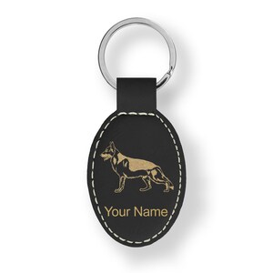 May include: Black leather oval keychain with a gold silhouette of a German Shepherd dog and the text "Your Name".