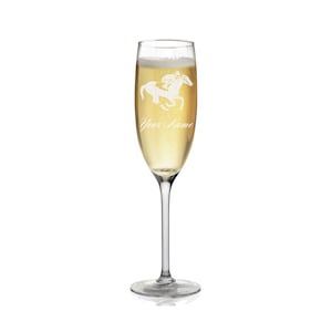 May include: A clear glass champagne flute with a white silhouette of a jockey riding a horse. The glass is filled with champagne and the text "Your Name" is engraved on the glass.