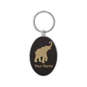 May include: A black oval keychain with a gold elephant silhouette and the text "Your Name".