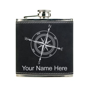 May include: A black flask with a silver top and a compass rose design. The flask has the text "Your Name Here" in white. The flask is rectangular and has white stitching around the edges.