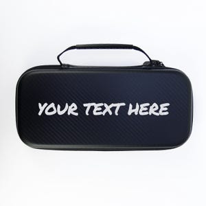 May include: A black carrying case with a textured surface and a handle. The text "YOUR TEXT HERE" is printed in white on the front of the case. The case has a zipper closure.