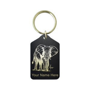 May include: Black metal keychain with a gold engraved image of an elephant. The keychain has a ring and the text "Your Name Here" is engraved below the image.