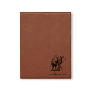 May include: A brown leatherette journal with an engraved image of an elephant and the text "Your Name Here".