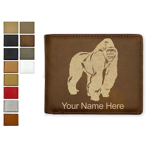 May include: A brown bifold wallet featuring a light-colored engraved graphic of a standing gorilla and the text Your Name Here. To the left, a vertical column displays a variety of color and texture swatches for the wallet, including black, red, and silver.