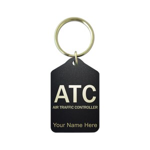 May include: Black rectangular keychain with a gold-colored ring. The keychain has the letters "ATC" in gold, with "AIR TRAFFIC CONTROLLER" below. The text "Your Name Here" is at the bottom. The keychain is a personalized gift.