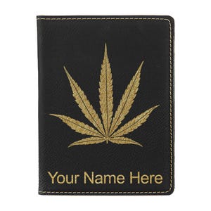 May include: Black passport holder with a gold cannabis leaf design and the text "Your Name Here". The holder is made of leather-like material and has gold stitching around the edges.