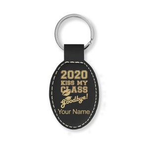 May include: Black leather oval keychain with gold lettering that reads "2020 Kiss My Class Goodbye!" and a graduation cap with a lip print. The keychain has a silver key ring and the text "Your Name" is at the bottom.