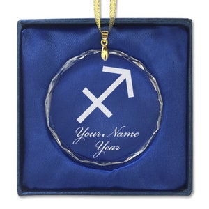 May include: A clear crystal ornament with a white Sagittarius zodiac symbol and the text "Your Name Year" on a blue velvet background.