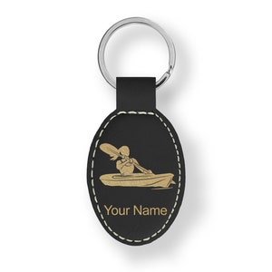 May include: Black leather oval keychain with a gold silhouette of a person kayaking. The keychain has a stitched border and the text "Your Name" is engraved below the image.