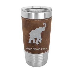 May include: A stainless steel travel mug with a brown faux leather wrap. The wrap features a gray elephant silhouette and the text "Your Name Here".