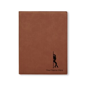 May include: A brown leatherette journal with a black silhouette of a woman on a pole. The text "Your Name Here" is printed below the image.