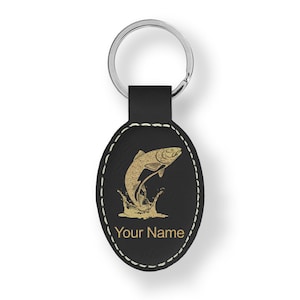 May include: Black leather oval keychain with a silver ring. The keychain features a gold illustration of a leaping fish with water splashes. The text "Your Name" is below the fish, with white stitching around the edge.