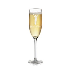 May include: A clear glass champagne flute with a personalized inscription that reads "Your Name". The flute is filled with champagne and features a white silhouette of a conductor with arms raised.