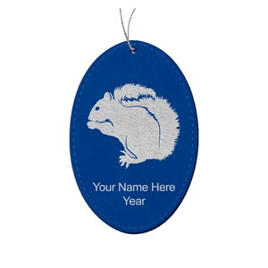 May include: Blue oval leather ornament with a white silhouette of a squirrel and the text "Your Name Here Year".
