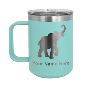 May include: A teal travel mug with a silver elephant silhouette and the text "Your Name Here." The mug has a handle, a clear lid, and a silver band at the top. It is designed to keep beverages hot or cold.
