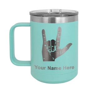 May include: A teal stainless steel travel mug with a silver lid and handle. The mug features a silver silhouette of the American Sign Language symbol for "I love you" and the text "Your Name Here".