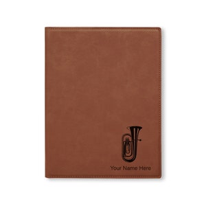 May include: Brown leatherette folder with a black silhouette of a tuba and the text "Your Name Here".
