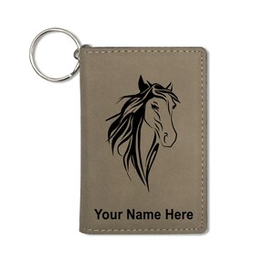 Puede incluir: Un llavero de cuero marrón con un diseño de cabeza de caballo negro y el texto "Your Name Here".