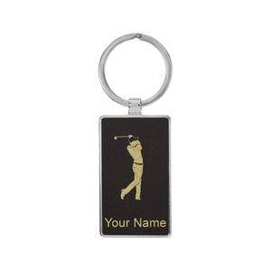 May include: A black leather keychain with a gold silhouette of a golfer swinging a club. The keychain has a silver ring and the text "Your Name" is printed in gold at the bottom.