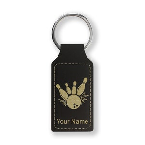 May include: Black leather keychain with a gold bowling pin and ball design. The keychain has a stitched border and the text "Your Name" is engraved on the bottom.