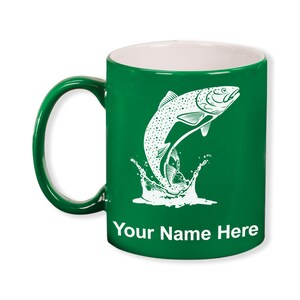 May include: A green ceramic mug with a white interior and handle. The mug features a white illustration of a fish leaping out of water, with the text "Your Name Here" at the bottom. The mug is designed for beverages.