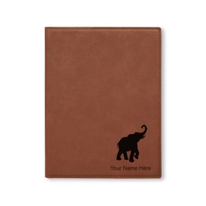 May include: A brown leather notebook with a black silhouette of an elephant and the text "Your Name Here" on the front.